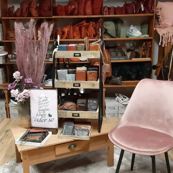 Liebevoll eingerichtete Ladenecke mit Taschen- und Portemonnaie-Auswahl, Trockenblumen und gemütlichem Sitzplatz