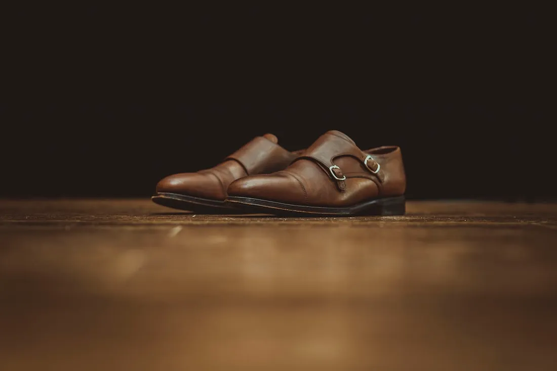 Brauner Herren-Lederschuh mit Schnalle auf warmem, dunklem Grund